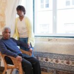 aide-soignante aidant une personne âgée à domicile dans son salon