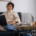 Femme concentrée écrit sur ordinateur portable dans un intérieur lumineux
