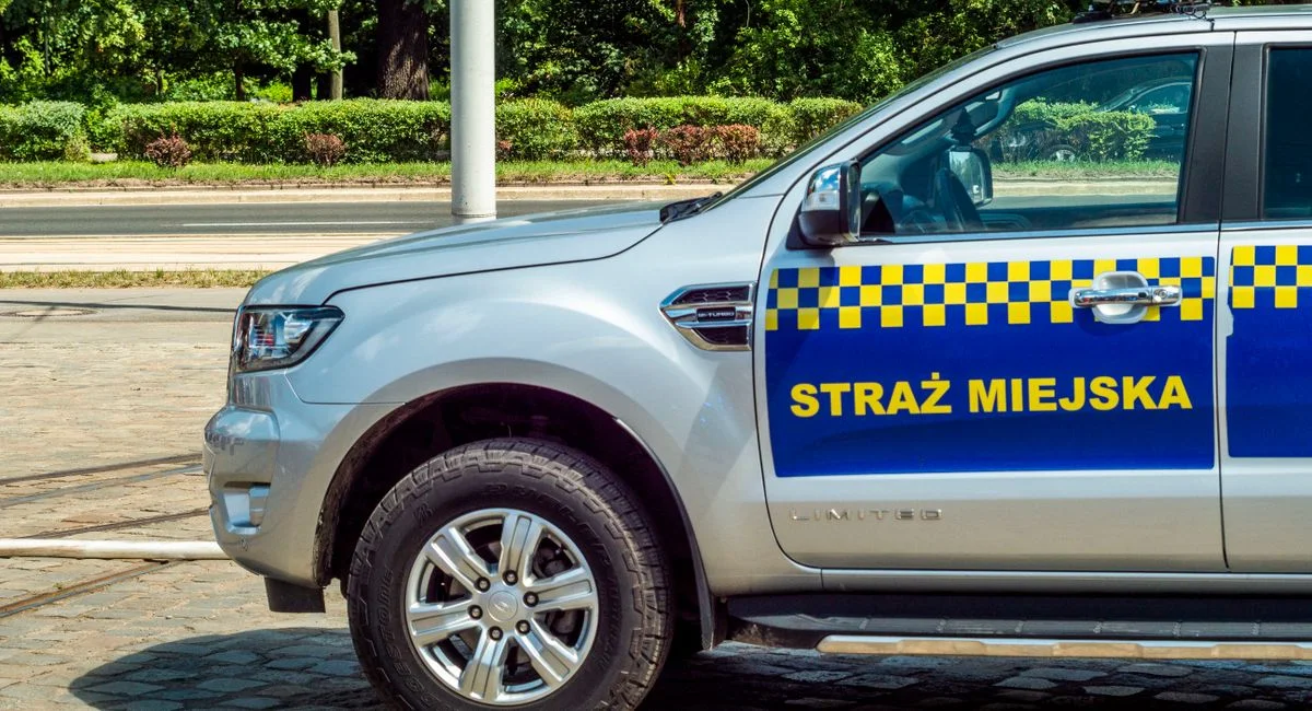 A municipal police vehicle parked on a cobblestone street during the day.